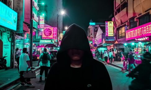 man in black hoodie walking on street during night time
