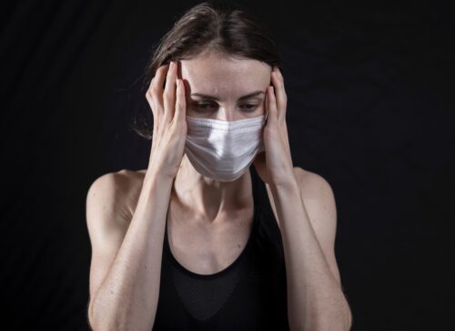woman in black tank top covering her face with her hands