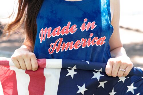 woman in blue sleeveless top holding flag of America