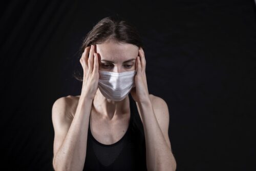 woman in black tank top covering her face with her hands