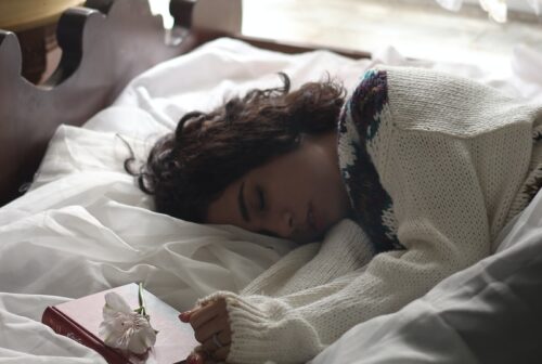 woman sleeping on bed beside book