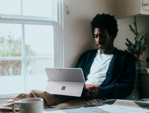 Man sitting by a window on his Surface laptop, Christmas tree in the background