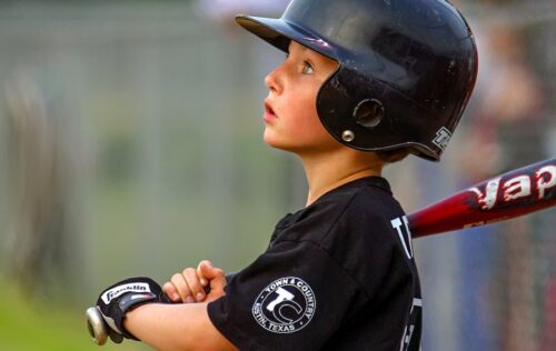 boy in black and white baseball jersey and helmet