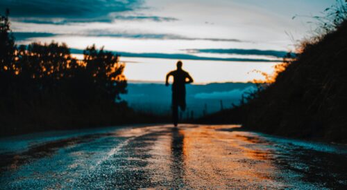 silhouette photo of a person running on road