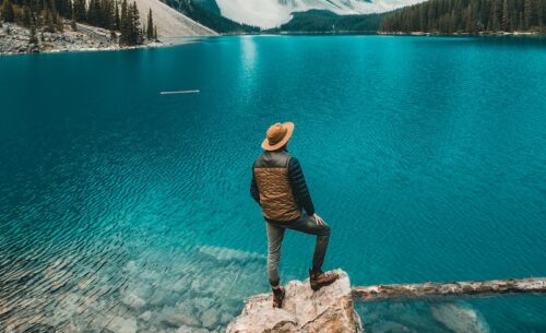 man standing on rock near lake