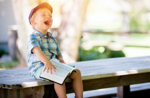 boy sitting on bench while holding a book