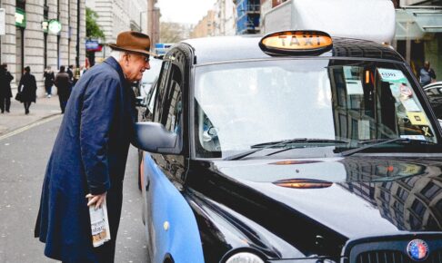 man talking through taxi car mirror during daytime