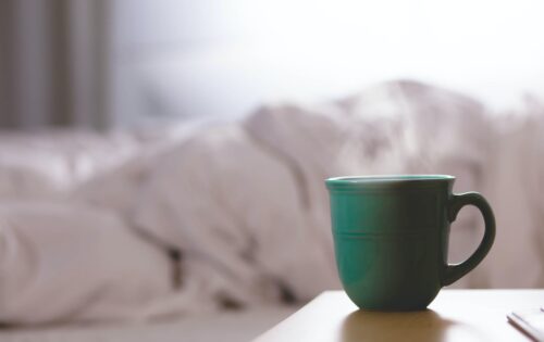 green ceramic mug on wooden desk