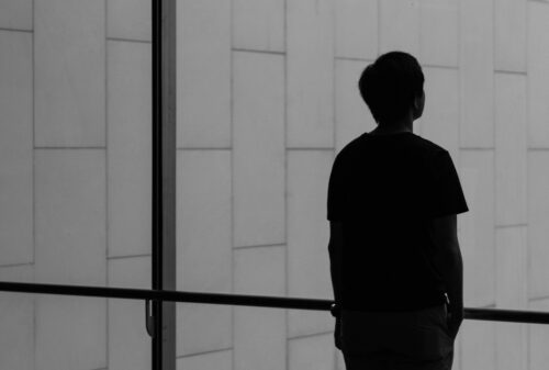 silhouette of a person facing glass wall