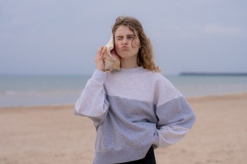 a woman is sitting on a bench on the beach