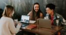 three people sitting in front of table laughing together