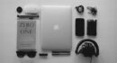 silver MacBook near black corded headphones and assorted items